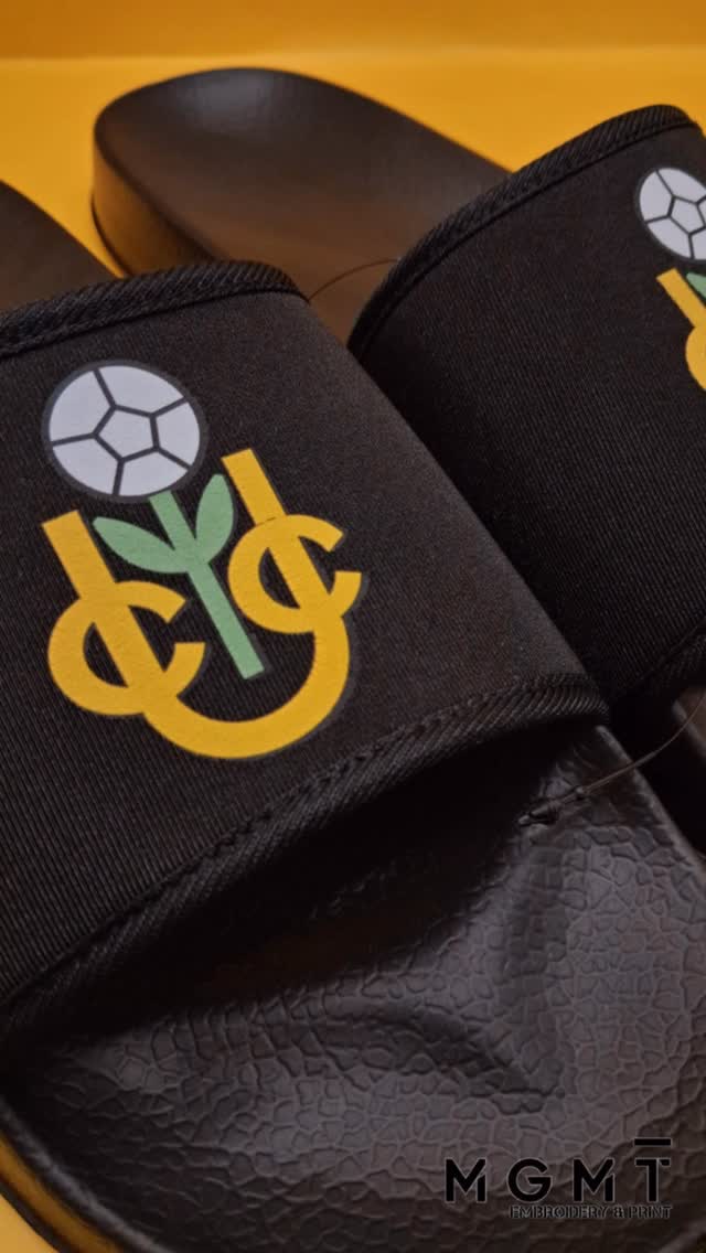 Custom comfort, but make it your brand 🔥From sports teams to dance studios, branded sliders are the perfect way to keep your logo on show on and off the pitch. ⚽💃Comfort meets style, fully personalised your way.📩 Get in touch to create your own.#MGMTEmbroideryAndPrint #CustomMerch #BrandedClothing #Personalised #Teamwear